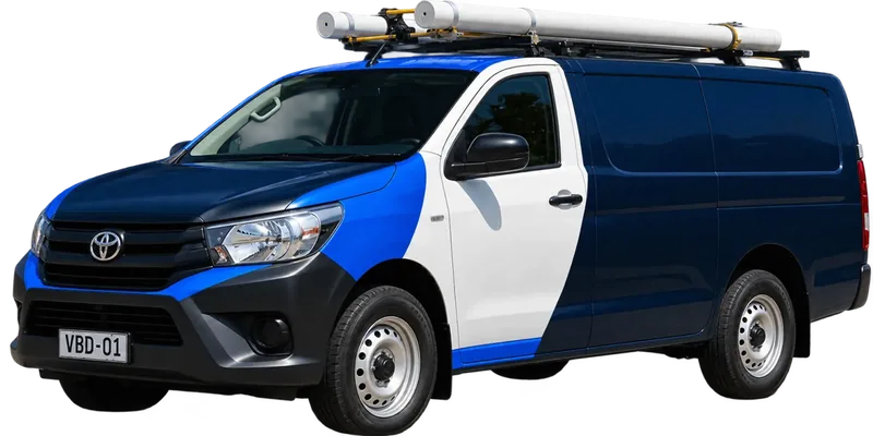 A licensed Newtown plumbing van loaded with pipe on the roof rack
